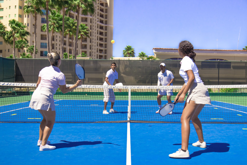 cuatro personas jugando pickleball en una cancha azul