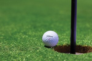 pelota de golf junto a un hoyo en el campo